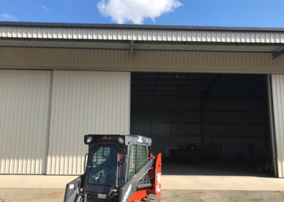Industrial shed with large sliding doors. With a bobcat in the front.